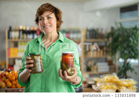 Woman chooses tomatoes and cucumbers in a marinade Woman chooses tomatoes and cucumbers in a marinade 133831898
