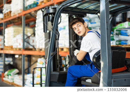 Young guy worker works on loader in warehouse Young guy worker works on loader in warehouse 133832006
