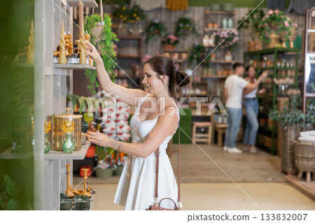 Woman in white dress buys candles and other gifts for family and friends in gift shop Woman in white dress buys candles and other gifts for family and friends in gift shop 133832007