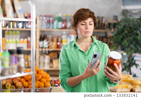Adult woman scanning qr code of pickled tomatoes Adult woman scanning qr code of pickled tomatoes 133832141