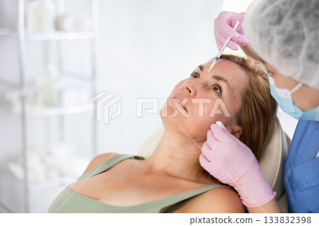 Woman getting procedure of injection contouring and lip augmentation for facial correction in clinic Woman getting procedure of injection contouring and lip augmentation for facial correction in clinic 133832398