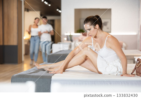 Adult woman chooses mattress in store Adult woman chooses mattress in store 133832430