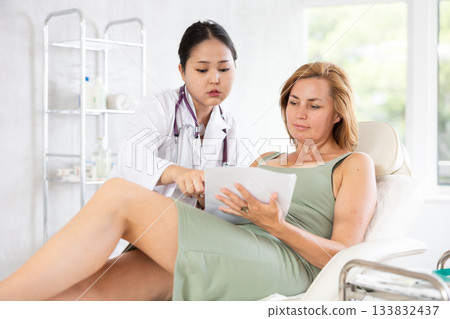 Middle-aged woman signing contract before having a medical operation in cosmetology clinic 133832437