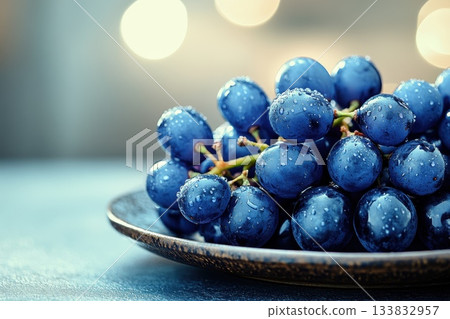Fresh Blue Grapes with Water Droplets on Plate Under Soft Blurred Background Lighting 133832957
