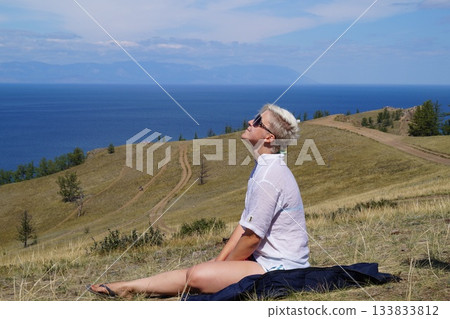 A girl rests at the peak of a mountain after climbing A girl rests at the peak of a mountain after climbing 133833812