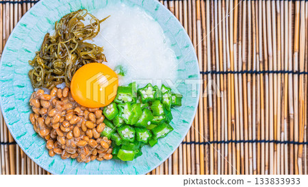 一碗香糯的夏日米飯，上面鋪著納豆、秋葵、山藥泥、海苔碎和蛋黃。 133833933