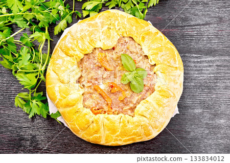Galette of minced meat with peppers on paper and board top Galette of minced meat with peppers on paper and board top 133834012