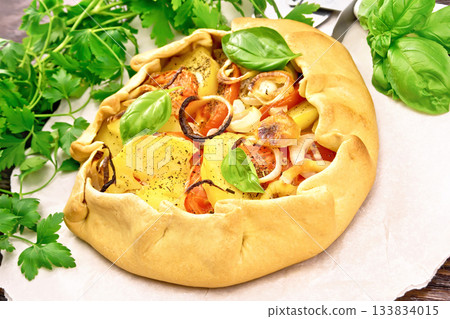 Galette of potato and tomato on dark board 133834015