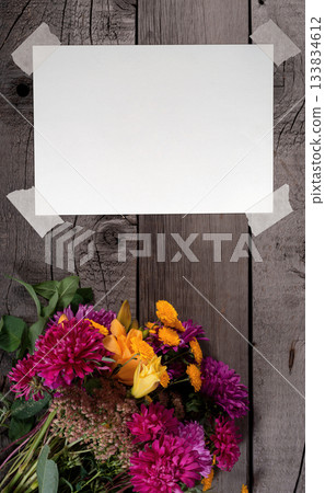 Blank Paper Sheet with Adhesive Tape on Wooden Rustic Table with Wild Colorful Rustic Flowers Bouquet from Daisy, Chrysanthemum and Others. File with Clipping Path. 133834612