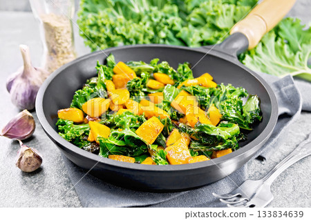 Kale with pumpkin in skillet on stone table 133834639