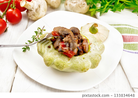 Patisson stuffed with liver and vegetables in plate on wooden board 133834648