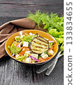 Salad of eggplant with feta and tomatoes on black board 133834655