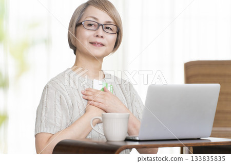 A senior woman staring at her bankbook and computer in the living room 133835835