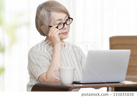 A senior woman staring at her bankbook and computer in the living room A senior woman staring at her bankbook and computer in the living room 133835838