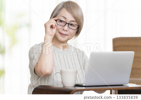 一位老婦人在客廳裡盯著她的存摺和電腦。 133835839