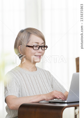 A senior woman staring at her bankbook and computer in the living room A senior woman staring at her bankbook and computer in the living room 133835863