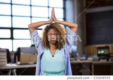 Woman standing inside modern open-plan office, surrounded by desks, monitors, paperwork and boxes 133836555