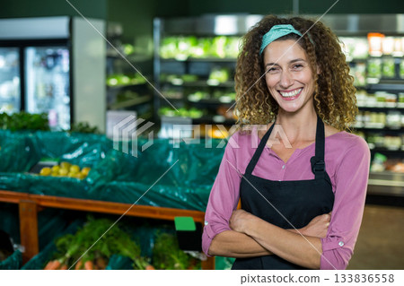 female employee arranging carrots on wooden tables with green liners in produce area, copy space 133836558