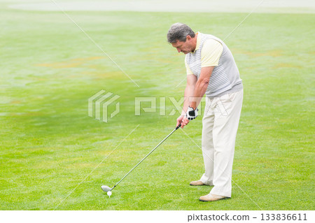 Senior African American man aligning golf club behind ball on tee at golf course, copy space 133836611