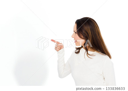 Woman pointing with right hand wearing white top in studio against blank background, copy space Woman pointing with right hand wearing white top in studio against blank background, copy space 133836633