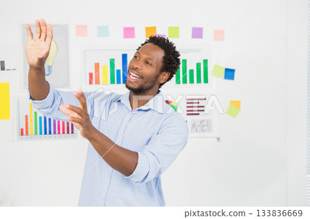 African American man in blue shirt standing in meeting room presenting bar charts and sticky notes 133836669
