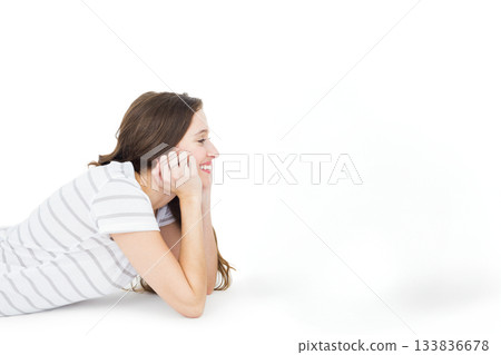 Woman in her twenties lying on seamless white studio surface, smiling and looking right, copy space Woman in her twenties lying on seamless white studio surface, smiling and looking right, copy space 133836678