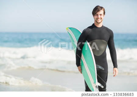 Male surfer emerging from waves at beach wearing wetsuit with green-white surfboard, copy space Male surfer emerging from waves at beach wearing wetsuit with green-white surfboard, copy space 133836683