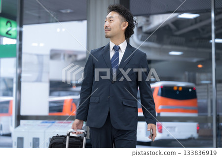 A middle-aged businessman in a suit walking through an airport or station 133836919