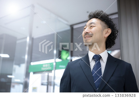 A middle-aged businessman in a suit walking through an airport or station 133836928
