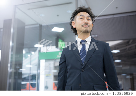 一位身穿西裝的中年商務人士正在機場或車站行走。 133836929