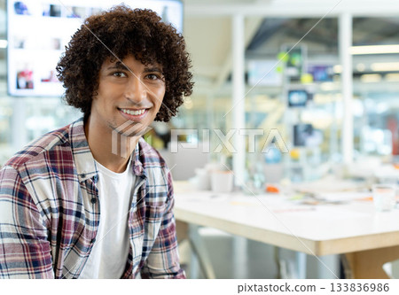 African American man sitting at desk in open-plan office, viewing display screen and smiling African American man sitting at desk in open-plan office, viewing display screen and smiling 133836986