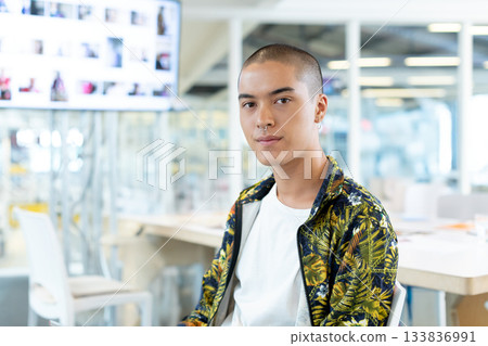 Asian man sitting at work table in creative studio reviewing thumbnail visuals on display Asian man sitting at work table in creative studio reviewing thumbnail visuals on display 133836991