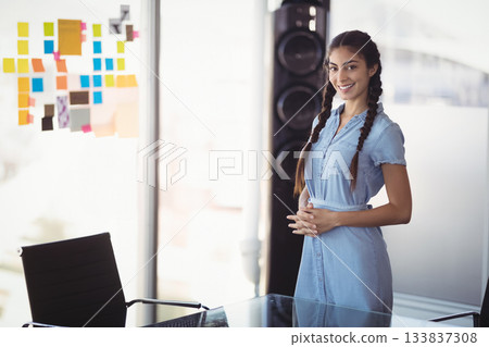 Female professional standing next to glass table with colorful sticky notes and speaker in office Female professional standing next to glass table with colorful sticky notes and speaker in office 133837308