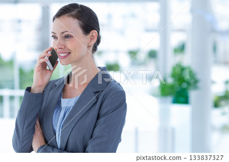Professional woman speaking on smartphone wearing blazer in modern lobby with plants, copy space Professional woman speaking on smartphone wearing blazer in modern lobby with plants, copy space 133837327