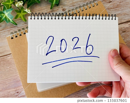 Hand holding a notebook with 2026 written on it 133837601