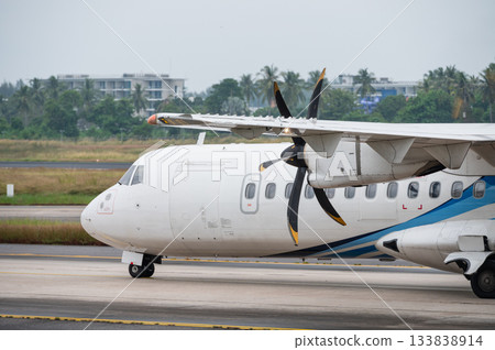 Regional turboprop aircraft taxiing on the runway with propeller visible 133838914