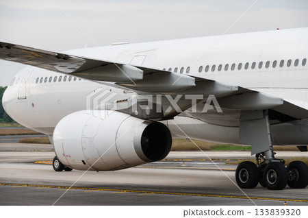 Wing and jet engine wide body aircraft on taxiway Wing and jet engine wide body aircraft on taxiway 133839320