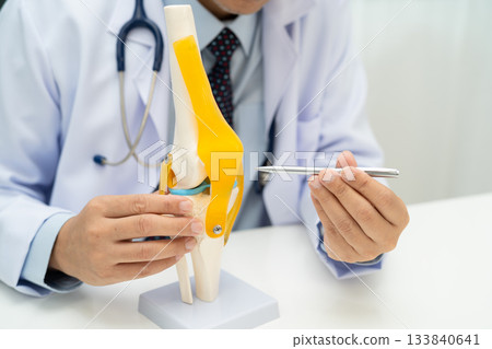 Asian doctor holding spinal nerve and bone model, Lumbar spine displaced herniated disc fragment for treatment medical in the orthopedic department. 133840641