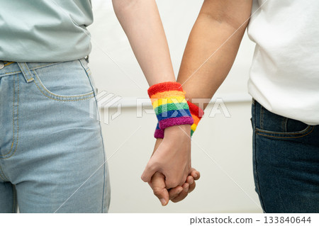 Asian LGBT couple woman holding hand wearing rainbow wristband. Asian LGBT couple woman holding hand wearing rainbow wristband. 133840644