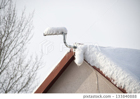 Snow-covered roof with a television antenna on a cold winter day Snow-covered roof with a television antenna on a cold winter day 133840888