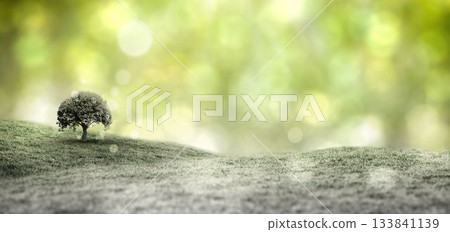 lone leafy tree is standing atop rolling grassy hill in flat design with green bokeh background 133841139