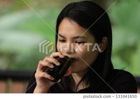 Young Asian woman drinking coffee in a restaurant in Thailand. Young Asian woman drinking coffee in a restaurant in Thailand. 133841650