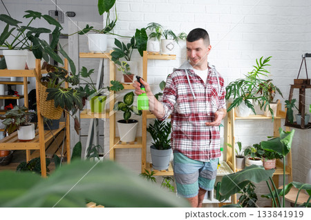 A man takes care of home potted plants on the shelves, spraying against pests, his business 133841919