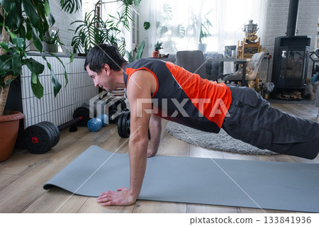 A man does push-ups at home on a fitness carpet 133841936