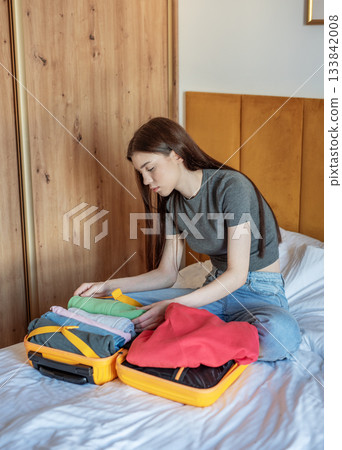 Woman packing clothes into suitcase for travel trip 133842008