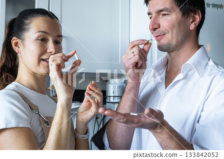 A man and a woman drink capsules with dietary supplements and vitamins in the kitchen 133842052