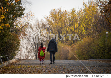 Yerevan Armenia 11.25.2025. A young girl and man walk down a path in the woods 133842396