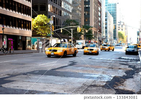 Yellow taxi cabs are cruising along worn downtown avenue under signals, signs by office towers Yellow taxi cabs are cruising along worn downtown avenue under signals, signs by office towers 133843081