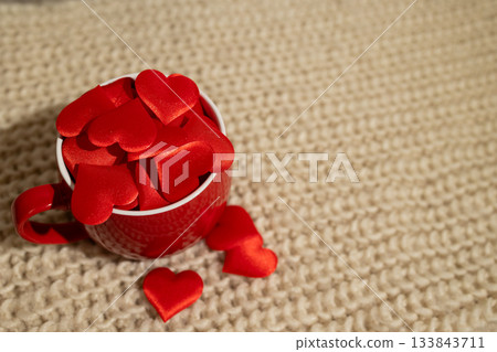 Valentine's Day Red Hearts Overflowing From a Cup on Knitted Wool Background Valentine's Day Red Hearts Overflowing From a Cup on Knitted Wool Background 133843711