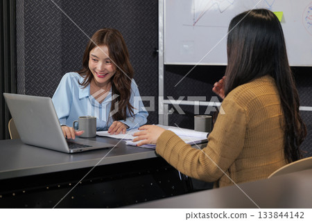 Business women meet, busy team people discuss important project work, meeting plans in modern conference room, smiling woman points to laptop screen during active collaboration. Business women meet, busy team people discuss important project work, meeting plans in modern conference room, smiling woman points to laptop screen during active collaboration. 133844142